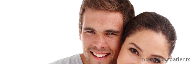 Smiling young couple posing cheek to cheek, showing even, white smiles (models, not actual patients)